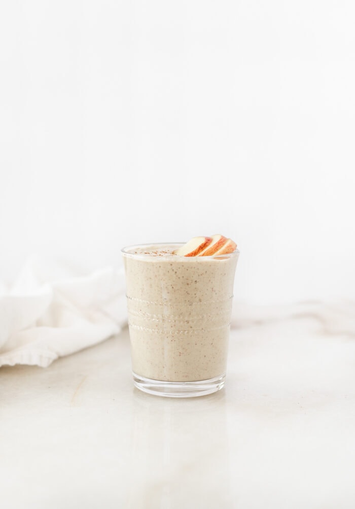 apple tahini smoothie with apple slices on top.
