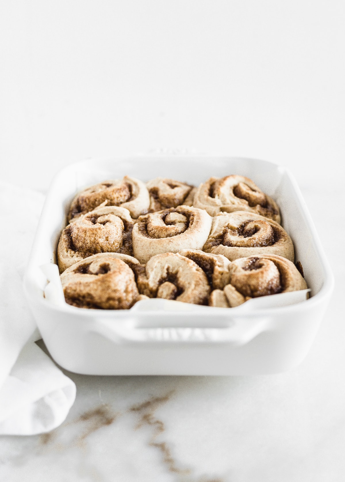 sourdough discard cinnamon rolls in a white baking dish after baking.