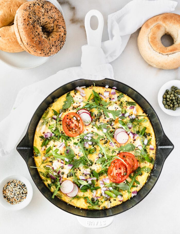 overhead view of an everything but the bagel lox frittata in a white cast iron skillet.