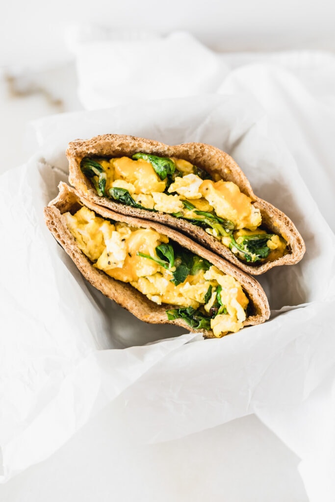 overhead view of two breakfast pita halves in a white basket lined with parchment.