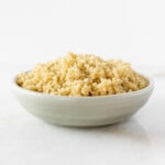 cooked quinoa in a small grey bowl on a white background.