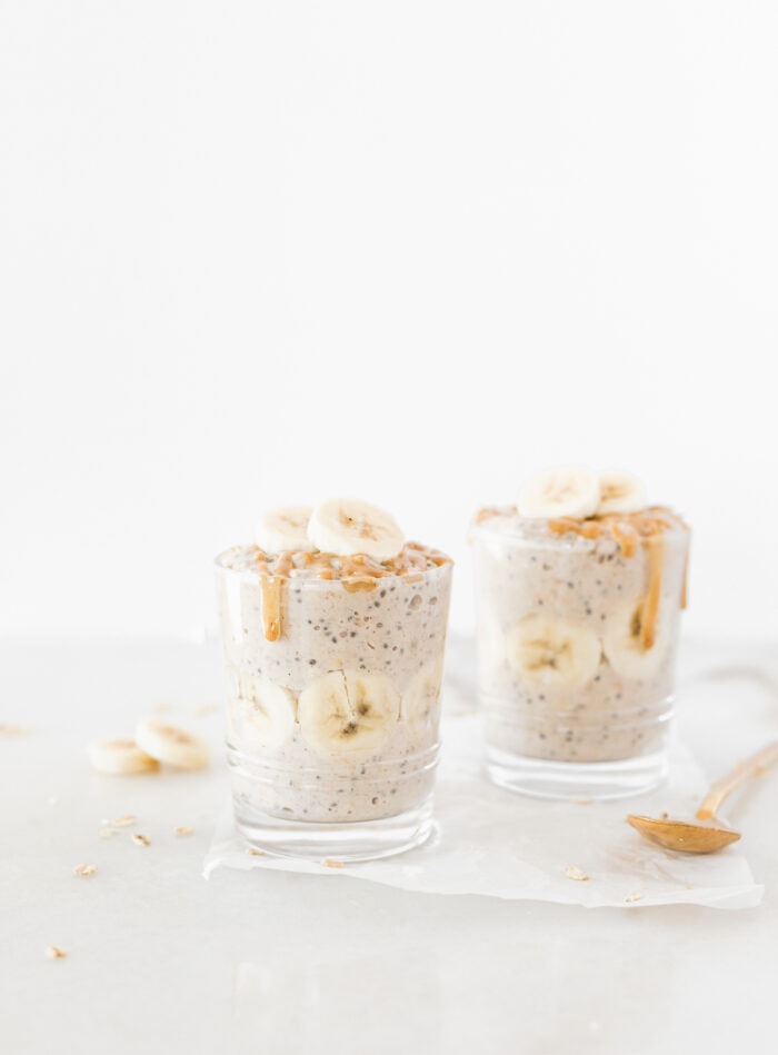 peanut butter banana overnight oats in two glasses drizzled with peanut butter and topped with banana slices.