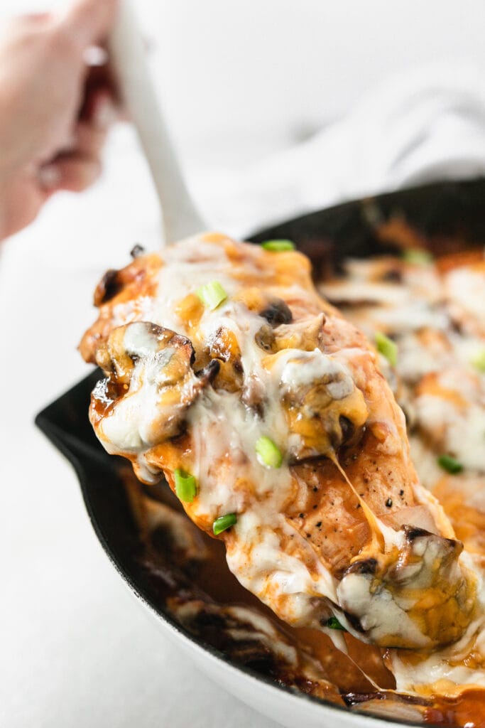 bbq mushroom chicken breast with cheese being pulled from a skillet.