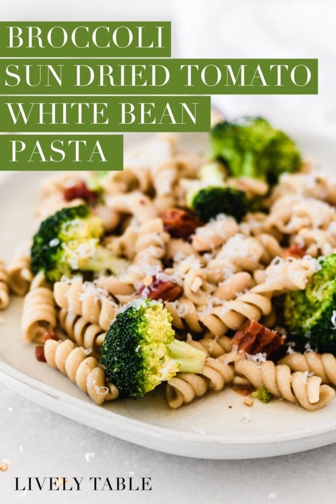 closeup of broccoli sun dried tomato white bean pasta on a grey plate with text overlay.